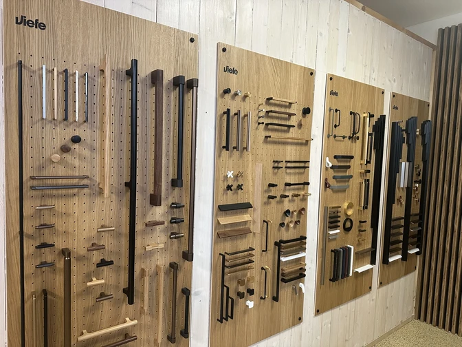 Úchytky VIEFE – vystavené modely úchytiek, vešiakov a zarážok v predajni CPS Interiér Nitra, v rôznych farbách a materiáloch (čierna, zlatá, mosadzná, drevená)